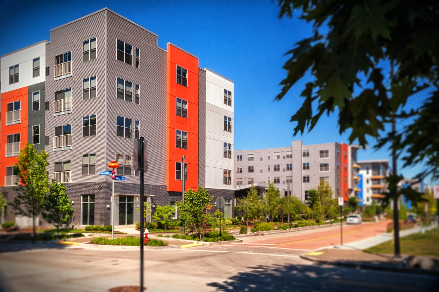 Street scene of condos at Bakery Living made with brightly colored architectural panels of red, blue, and gray. 