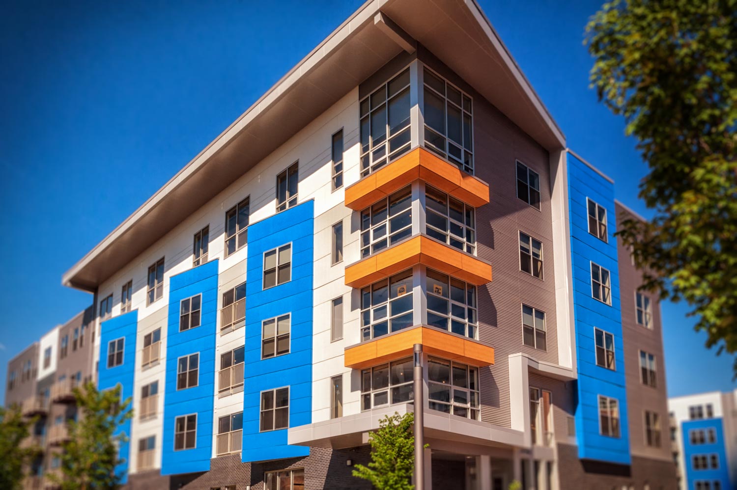 Street scene of condos at Bakery Living made with brightly colored architectural panels of red, orange, blue, and gray louvered panels
