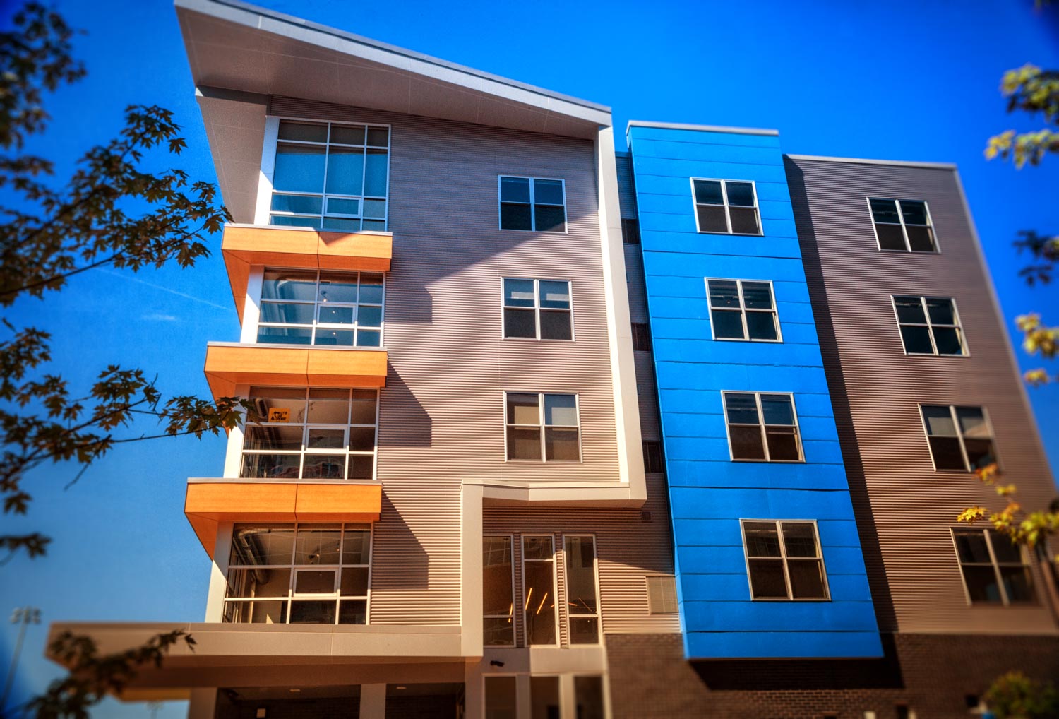 Photo street scene of condos at Bakery Living made with brightly colored architectural panels of red, orange, blue, and gray louvered panels