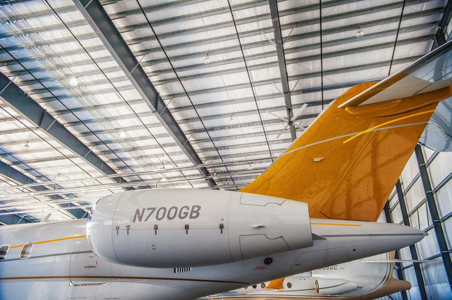 Inside hanger photo with yellow tail section of airplane LJ & Associates